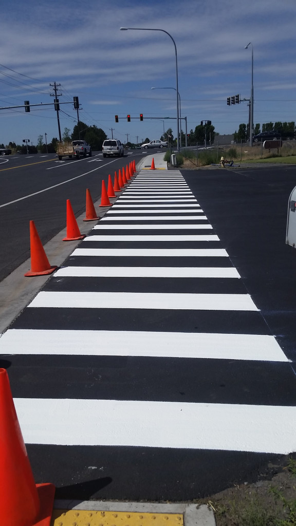 A street with orange cones and white lines.