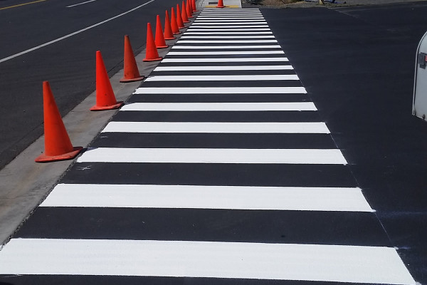 A street with orange cones and white lines.
