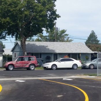 A view of a property, cars, and pavement with yellow lines