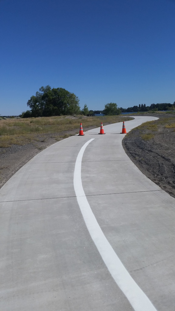 A road with white lines and orange cones on it.