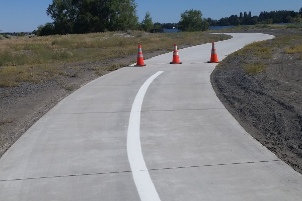 A road with white lines and orange cones on it.